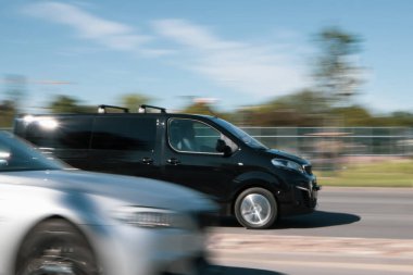 Siyah Peugeot Gezgini yoğun trafikte caddede araba sürüyor. Hareket bulanıklığı. Riga, Letonya - 15 Haziran 2021.