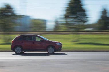 Caddede kırmızı bir Mitsubishi ASX sürüyor. Hareket bulanıklığı. Riga, Letonya - 15 Haziran 2021.