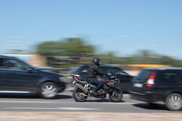 Yoğun trafikte motosiklet yüksek hızda sürer. Hareket bulanıklığı. Riga, Letonya - 15 Haziran 2021.