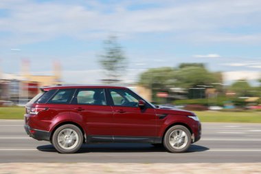 Kırmızı Land Rover Range Sport son sürat yolda ilerliyor. Hareket bulanıklığı. Riga, Letonya - 28 Haziran 2021.