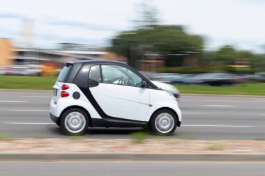 Hareket bulanık küçük araba. White Smart ForTwo caddede ilerliyor. Riga, Letonya - 06 Ağustos 2021.