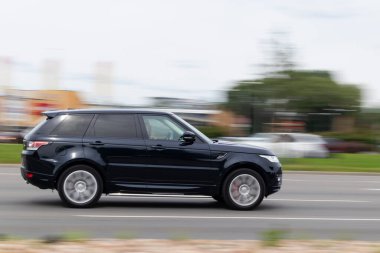 Land Rover Range Rover Sport caddede geziyor. Hareket bulanıklığı. Riga, Letonya - 06 Ağustos 2021.