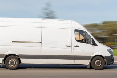 Beyaz bir kargo otobüsü caddede ilerliyor. Minibüsle şehirden şehire nakliye. Hareket bulanıklığı.