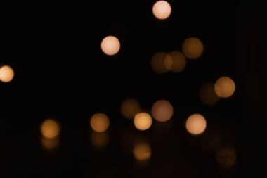Bulanık, bulanık arka plan ve bokeh etkisi. Siyah zemin üzerinde sarı ışık daireleri.