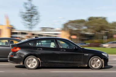 Siyah bir araba caddede ilerliyor. Hız limitini aşıyor. Hareket bulanıklığı. Riga, Letonya - 09 Sep 2021