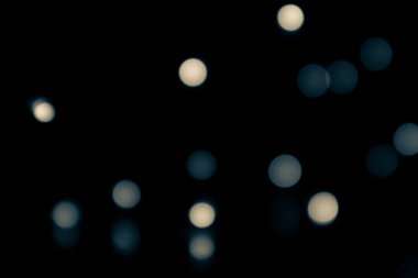 Bulanık, bulanık arka plan ve bokeh etkisi. Mavimsi ve sarımsı ışık siyah bir arkaplan üzerinde daireler çiziyor.