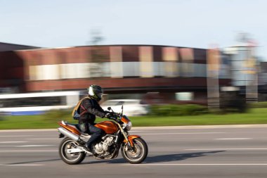 Altın rengi bir Honda motosikleti yüksek hızda caddede ilerliyor. Hareket bulanıklığı. Riga, Letonya - 09 Sep 2021.