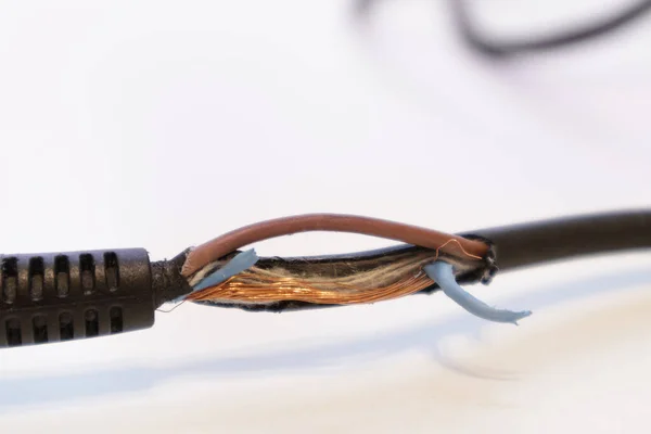 Broken power cord for home electrical appliances, electric tools. Damaged cable insulation. Close-up, soft focus.