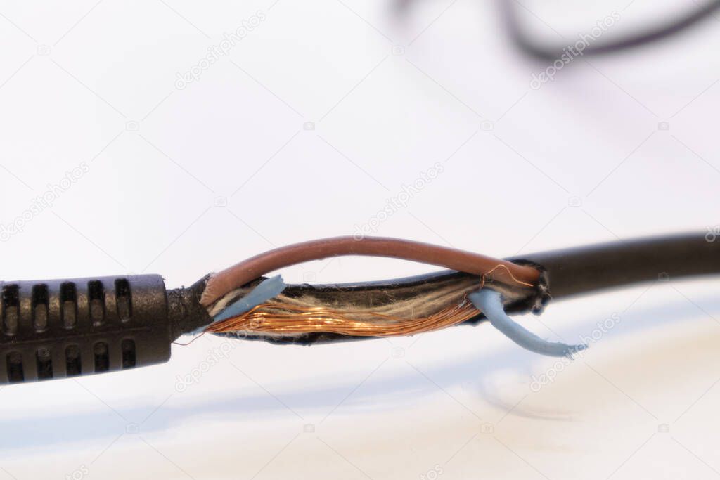Broken power cord for home electrical appliances, electric tools. Damaged cable insulation. Close-up, soft focus.