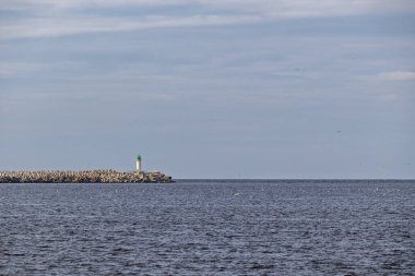 Dalgakıran ve deniz feneri olan bir deniz pelerini. Dalgakıranın sonundaki deniz feneri..