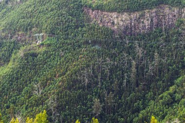Yeşil dağ manzarası. Dik bir dağ yamacında, sık yeşil bir ormandan geçen kablo araba..
