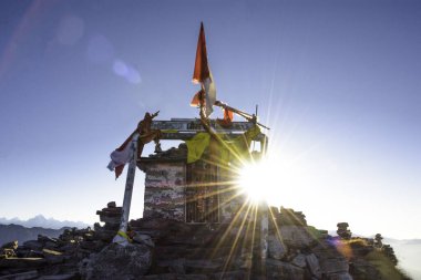 Dağların tepesinde sırt çantalı bir adamın silueti.