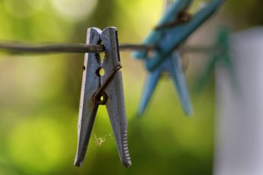 Eski mandallar dışarıda asılı, arka planda bulanıklık, seçici odaklanma. Yan görünüm.