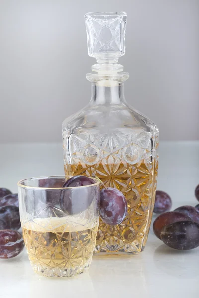 Plommon och brandy på vit bakgrund — Stockfoto