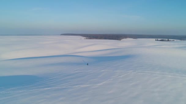 飞越白雪覆盖的田野。长山的阴影。男人独自旅行. — 图库视频影像