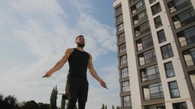 Genç bir adam yüksek bir binanın önünde atlayan bir ipe atlıyor..