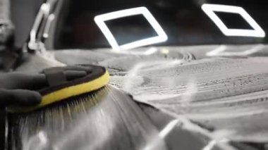 Elle oto yıkama. İşçiler köpüğü süngerle ovalarlar..