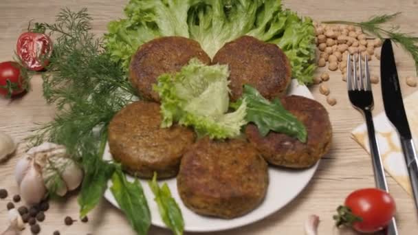 On a white plate, chickpea cutlets are decorated with lettuce, dill, spinach. — Stockvideo