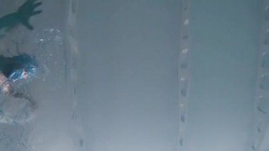 Bir adam koruyucu bir tıbbi maskeyle havuzda yüzer..