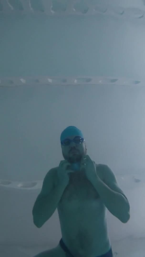 Mężczyzna pływa w podwodnym basenie i nosi maskę medyczną.. — Wideo stockowe