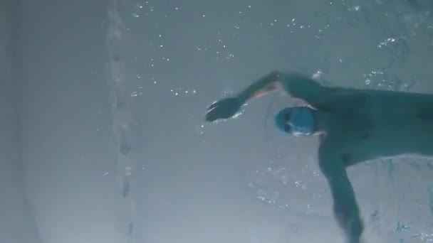 Een man zwemt in een zwembad onder water met een beschermend medisch masker. — Stockvideo
