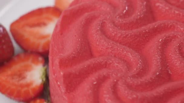 Κοντινό πλάνο ενός ροζ κέικ φράουλα στροβιλίζεται σε ένα λευκό πιάτο. — Αρχείο Βίντεο