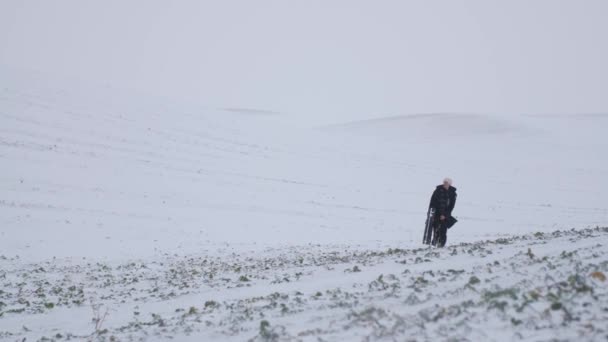 雪のフィールドを歩く場合にはギターを持つ疲れ、冷凍男. — ストック動画