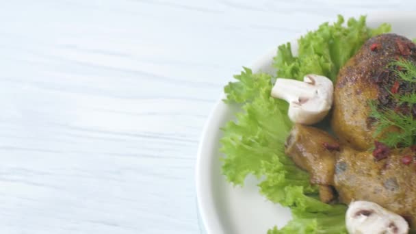 Coxas de frango fritas decoradas com cogumelos e alface giram em uma chapa. — Vídeo de Stock