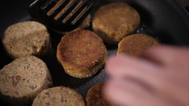 Braadkoteletten in een pan. De kok draait ze om met een spatel.. — Stockvideo