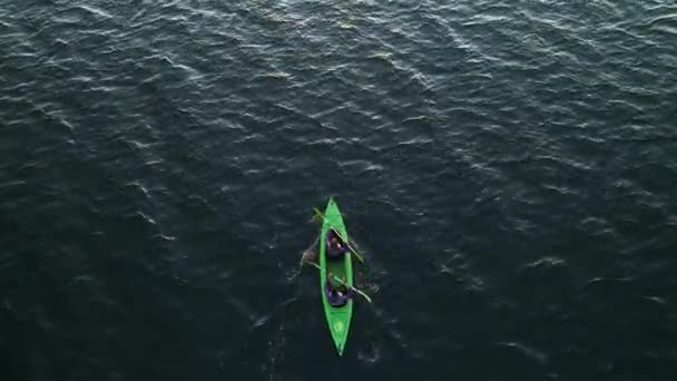 Young man and woman in a green kayak paddle. — Stock Video