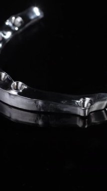 Titanyum diş yapısı koyu siyaha karşı kıvrımlı kemer ve eklem elementleri gösteriyor. Keskin kenarları implant bağlantısını ve güçlü sabit dikey videoyu desteklerken, şekillendirilmiş metal diş çizgisini takip eder