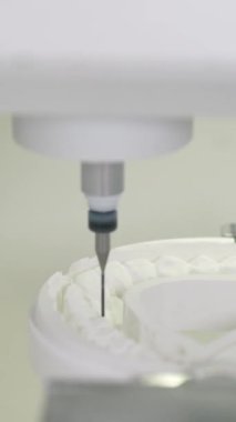 CNC sistemi, beyaz diskin diş protezini değirmende öğütüyor ve laboratuvarda sürekli besleme azalıyor. Kesme makinesi, taç biçimlerini şekillendirir implant prizlerini dikey görüntü gösteren pürüzsüz yüzey hazırlar