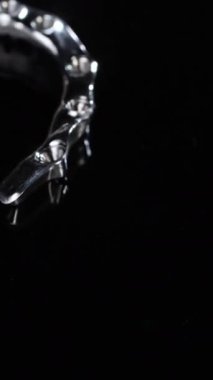 Titanyum diş yapısı koyu siyaha karşı kıvrımlı kemer ve eklem elementleri gösteriyor. Keskin kenarları implant bağlantısını dikey video desteklerken, şekillendirilmiş metal diş çizgisini takip eder