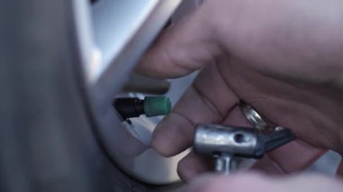 Tamirci lastik şişirme işlemine başlamadan önce ince pompa hortumunu bağlar. Uzman, nesne yüzeyinin bütünlüğünü incelemek için araç tekerleğinin gücünü geri getirmek için araç kullanır