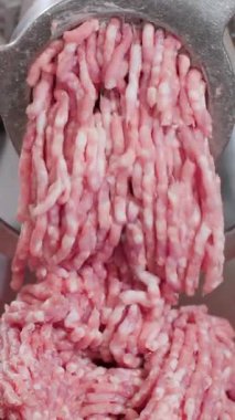 Dikey video. Kıyma parçaları öğütücüden yavaşça çıkar ve büyük tabağa düşer. Elektrikli cihaz malzemeleri işler ve uygun gıda üretimi için son parçaları oluşturur.