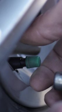 Dikey video. Tamirci lastik şişirme işlemine başlamadan önce ince pompa hortumunu bağlar. Uzman, nesne yüzeyinin bütünlüğünü incelemek için araç tekerleğinin gücünü geri getirmek için araç kullanır