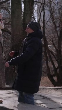 Dikey video. Zarif yaşlı kadın, bahar parkında sevgili kocasını kucaklamak için korkuluk boyunca yürür. Romantik son sınıf öğrencisi, karısını kucaklayarak şehir sokaklarında aşk duygularını ifade ediyor. Olgun insanlar çıkıyorlar