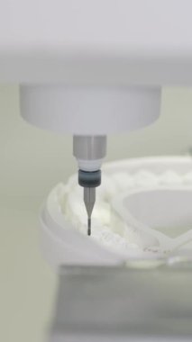 Hassas değirmen makinesi dişçi zirkon laboratuarının dairesel beyaz seramik malzemesi üzerinde çalışıyor. Temiz klinik ortam dikey videosunda kesme aracı öğütücüleri yüksek doğruluk takma dişleri ile şekillendiriliyor