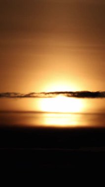 Güneş, turuncu gökyüzünde sakin bir şekilde batıyor. Hafif bulutlar, dikey görüntüler. Alacakaranlık vakti, boş karlı vadide parlak gün batımı ışığı. Resim günü sona eriyor