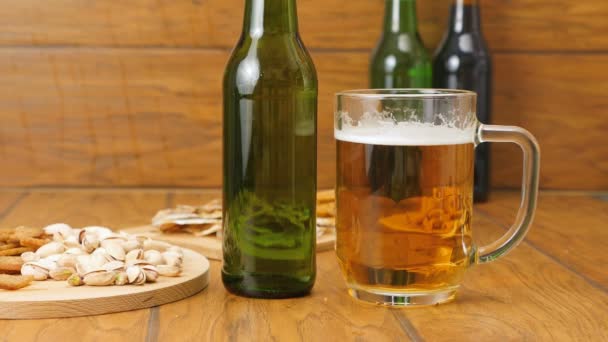 Composizione di birra, cracker, pistacchi, pesce essiccato. Una mano prende una birra — Video Stock