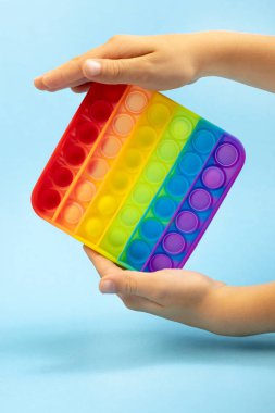 Silikon oyuncak anti-stresi patlat. Yeni moda. Mavi arka planda, çocukların elinde basit bir gamze..