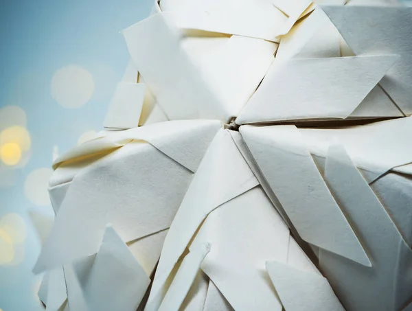 Beyaz kusudama origami topunun, arka planda sarı ışık ve mavi beyaz ışıkla çevrili görüntüsünü kapat