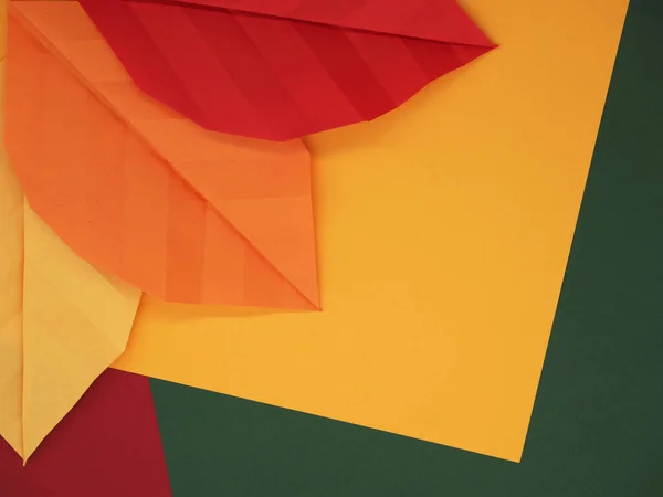 Kağıt origami yaprakları sonbahar temalı kağıtta sarı, yeşil ve kırmızı arka plan