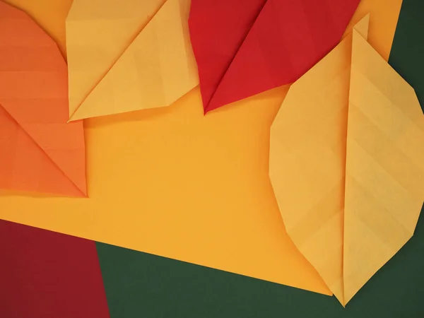 Kağıt origami yaprakları sonbahar temalı kağıtta sarı, yeşil ve kırmızı arka plan