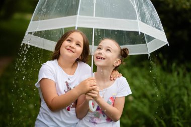 Yaz parkında şemsiye altında gülümseyen genç ve çekici kızlar.