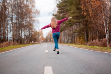 Kırsal kesimde boş yolda yürüyen bir kadın. Macera, spor, egzersiz, özgürlük ve hareket.