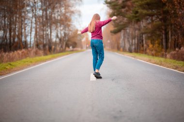 Kırsal kesimde boş yolda yürüyen bir kadın. Macera, spor, egzersiz, özgürlük ve hareket.
