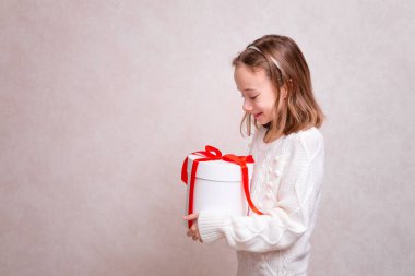 Beyaz kazaklı çocuk hediye kutusuyla tıbbi maske takıyor. Alışveriş. Boşluğu kopyala. 