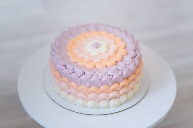 Sütlü krema ve ahududu dolu beyaz pasta yuvarlak cam bir tabakta. Beyaz, pembe, mor ve turuncu kremalı pasta..
