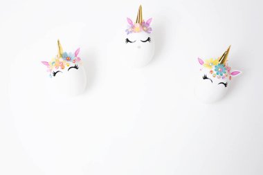 Beyaz arka planda tek boynuzlu at etiketleriyle süslenmiş Paskalya yumurtaları. Uzayı kopyala Üst Manzara. Paskalya için arkaplan.